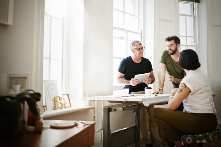 Shot of a group of designers using a tablet while brainstorming in the office